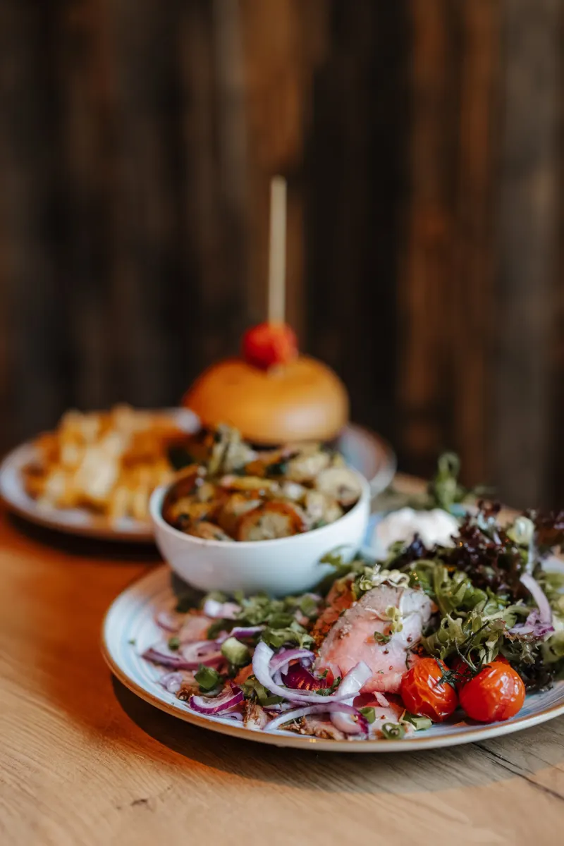 Salat und Burger auf einem Holztisch, fotografiert für Social Media